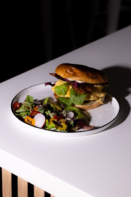 Frühstücksburger mit Rührei, Bacon und Salat